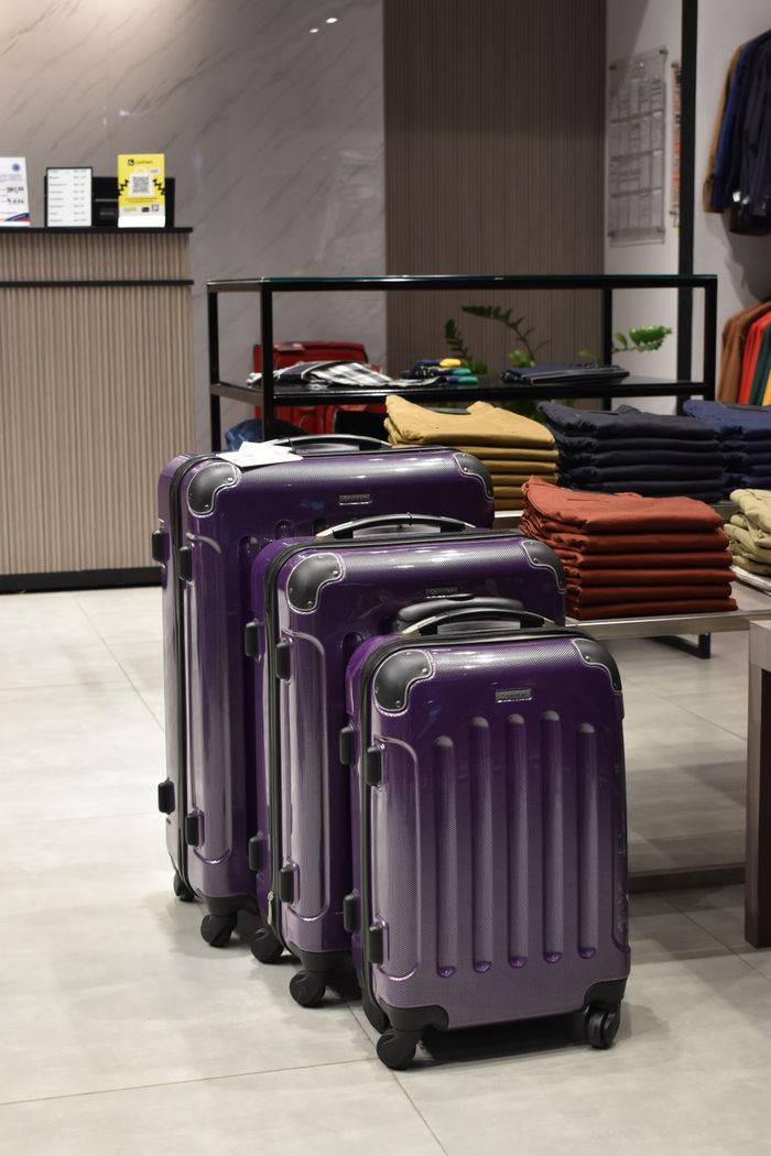 Stylish purple suitcases arranged in a clothing store offering modern travel essentials.